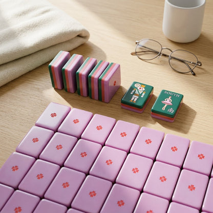 A field of tiles face-down showing the soft lilac backs and their centre flower, with a few stood on edge to show the red band