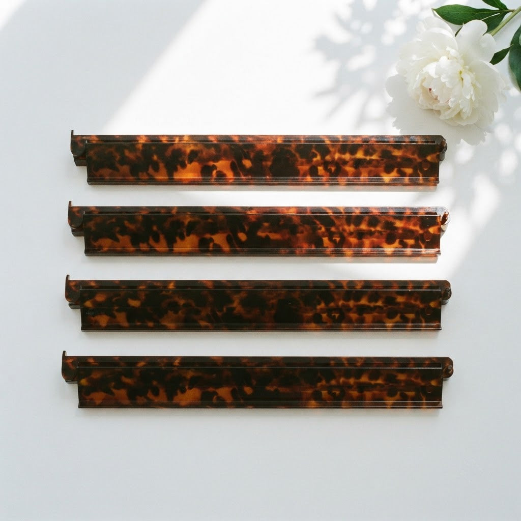 Four Tortoise Shell mahjong racks side by side from above beside a white peony