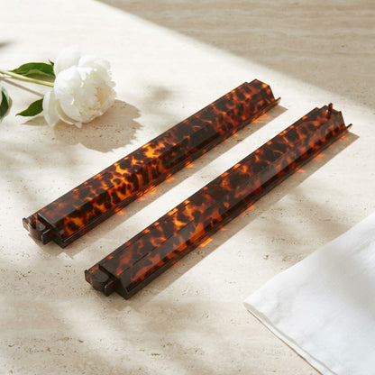 Two Tortoise Shell mahjong racks on a travertine table beside a white peony