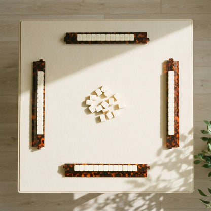 A mahjong table for four from above with a Tortoise Shell rack at each seat and tiles resting on every rack