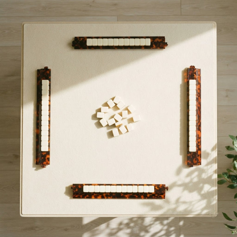 A mahjong table for four from above with a Tortoise Shell rack at each seat and tiles resting on every rack